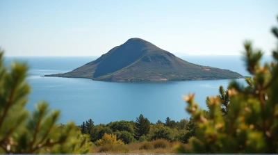 Rugged Green Hill Beside Tranquil Lake Under Clear Sky