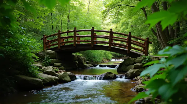 Rustic mahogany bridge arches above a clear creek surrounded by vibrant emerald foliage.