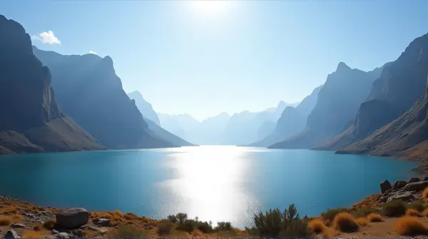 Shimmering Lake Near Rocky Peaks Under Bright Sky