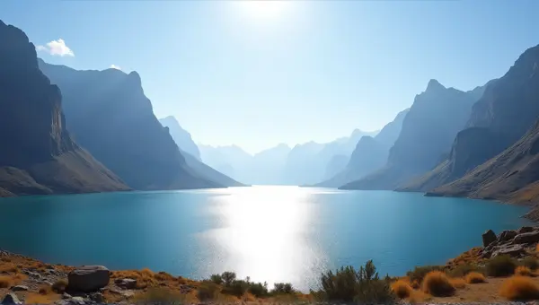 Shimmering Lake Near Rocky Peaks Under Bright Sky