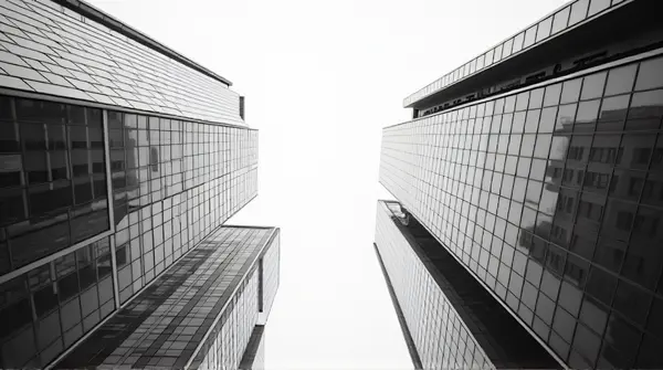 Monochrome low angle view of skyscrapers highlighting geometric window patterns against pale sky