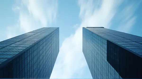 Low angle view of tall skyscrapers with blurred streaks of clouds moving above against a clear sky