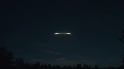 Slender Arc Of Light Over Silhouetted Trees