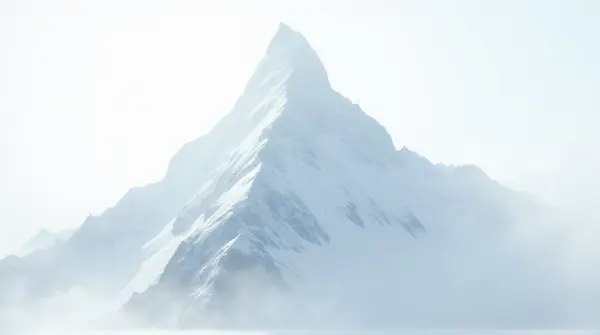 Sharp white-capped peak with frosted slopes beneath a pale, diffused sky