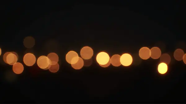 Close-up of soft glowing orbs of light scattered across a nighttime scene with varied sizes and hues