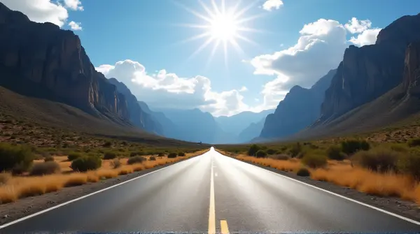 A sunlit asphalt path stretches between tall rocky peaks with sparse plants and a bright sky with clouds.