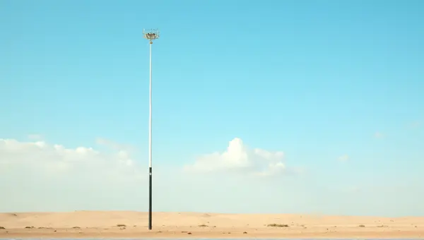 Tall Metal Pole On Dry Earth With Clear Sky