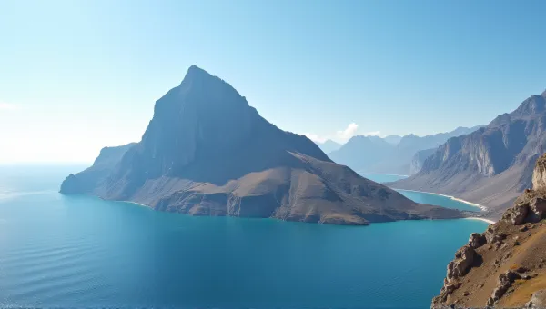 Tall Mountain Peak Next To Large Water Body Under Clear Sky