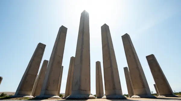 Low angle view of tall stone pillars rising sharply beneath a wide sky.