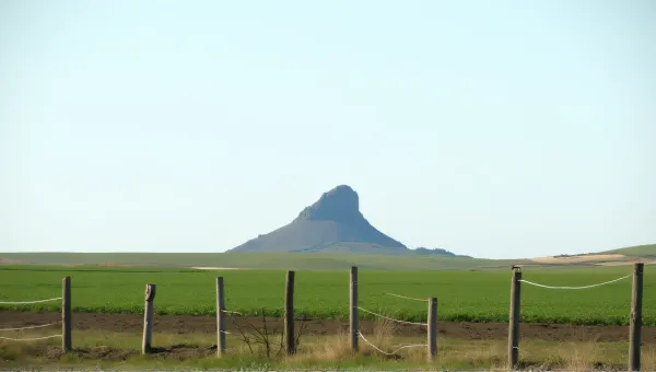 Towering Peak Over Cultivated Field Landscape