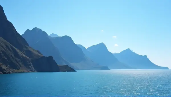 Towering Peaks Over Shimmering Water Under Clear Sky