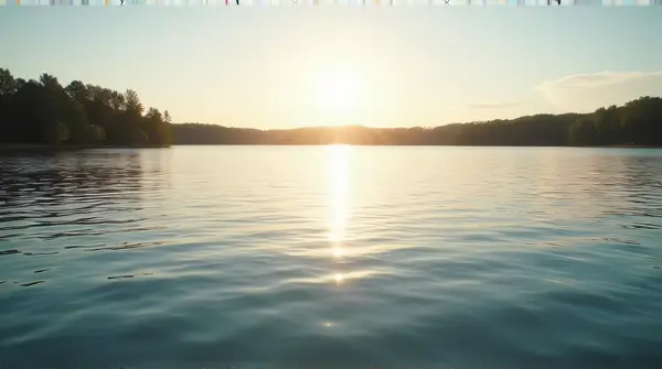 A peaceful lake with gentle ripples and soft warm light casting long shadows from distant trees under a clear sky.