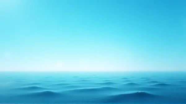 Gentle sunlight illuminates rippling sea waves beneath a wide clear sky at sunrise