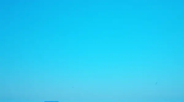 A wide cerulean sky stretches over a dark silhouetted horizon, highlighting vast openness above.