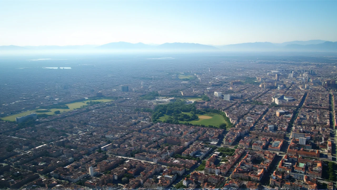 Aerial view of a city with grid streets, parks, and mountains in the distance.