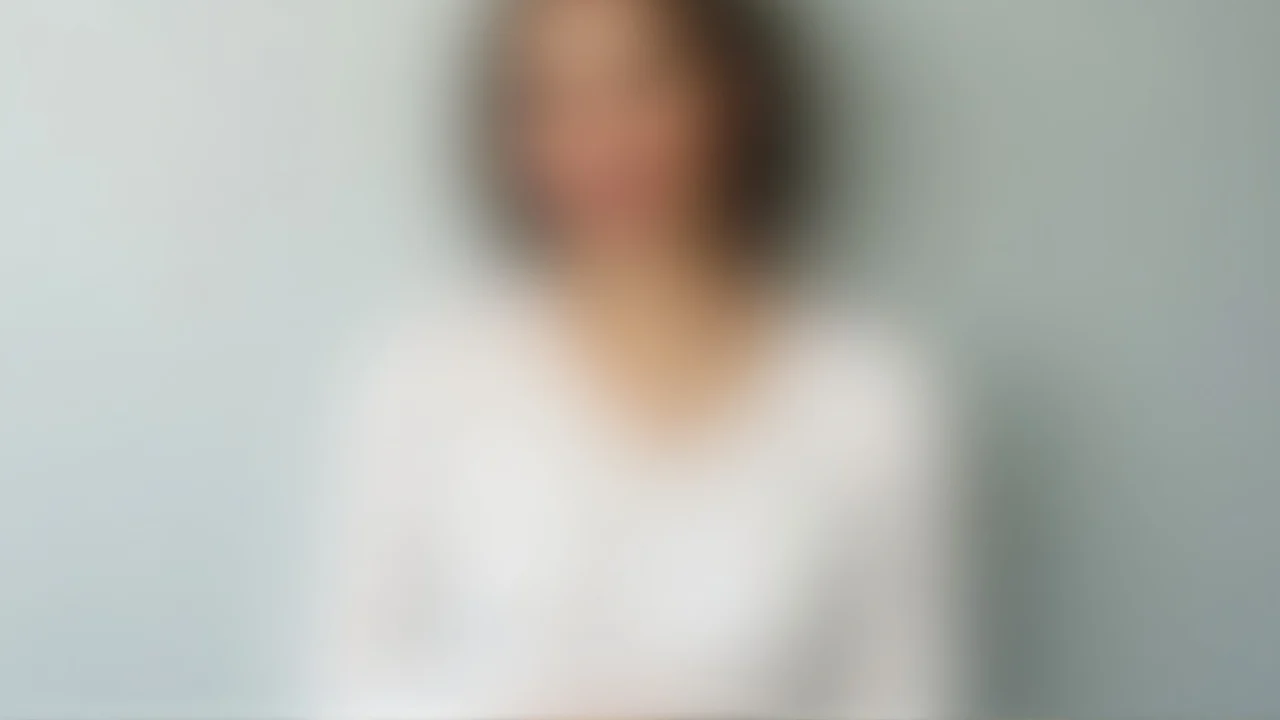 A person in a white long-sleeve top poses in a studio.