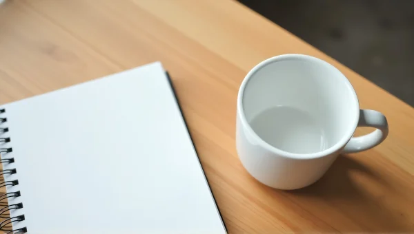 Ceramic Cup And Notebook On Wooden Desk