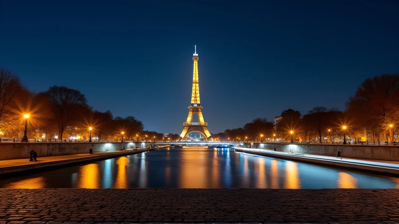 Nighttime view of the Eiffel Tower and Seine River with light reflections under a starry sky.