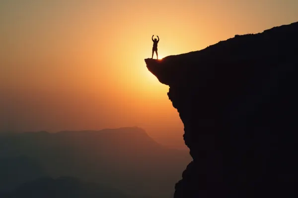 Lone Climber Silhouette at Dusk on Cliff Edge