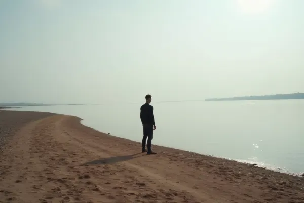 Lone Man Standing On Brown Shoreline Near Water