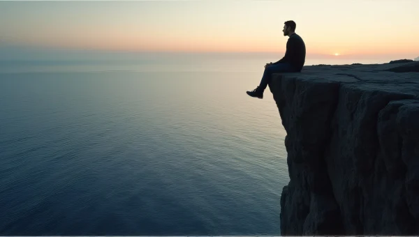 Man Sitting at Cliff Edge Overlooking Sea Dusk