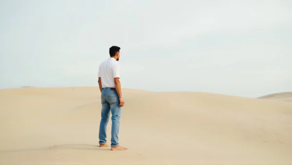 Man Standing on Wind-Swept Sand in Denim Outfit