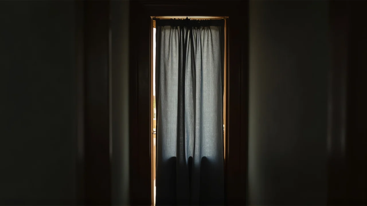 A narrow hallway featuring a gray curtain and soft side lighting.