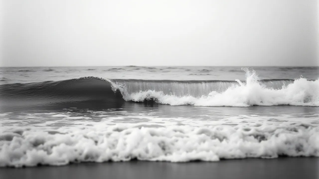 Black and white photo of ocean waves crashing onto the shore with a textured, high-contrast appearance.
