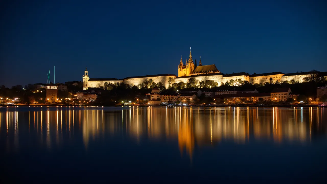 Nighttime view of Prague Castle lights reflecting on a peaceful lake.