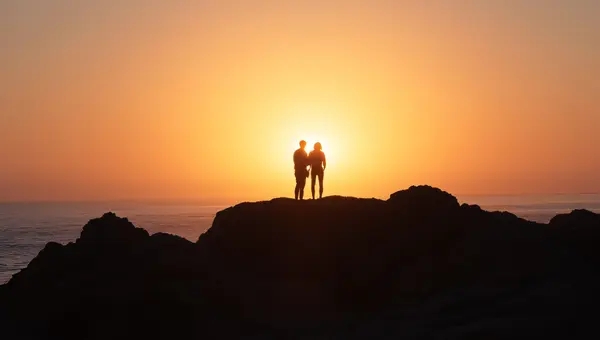 Silhouette of People on Coastal Rock at Sunset