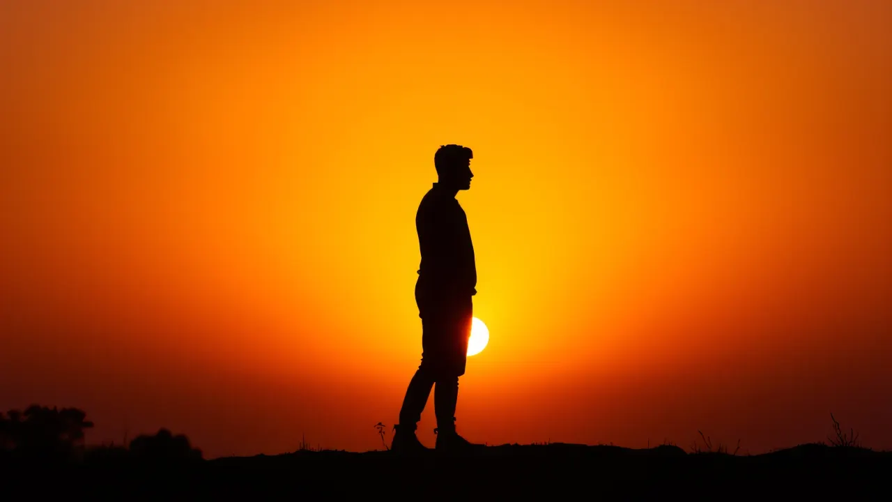 A lone person's silhouette stands against a vibrant sunset, showcasing a serene moment of solitude.