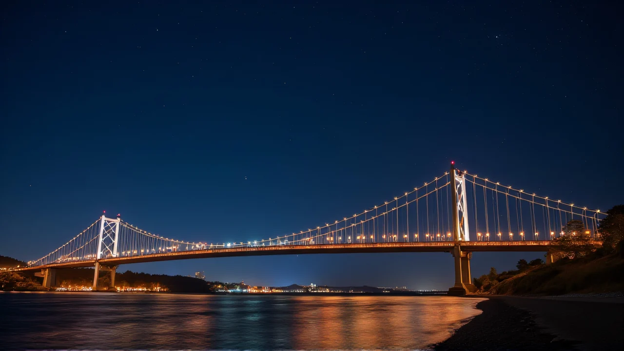 A low-angle view of a suspension bridge illuminated by warm lamps spanning a river under a starry sky.