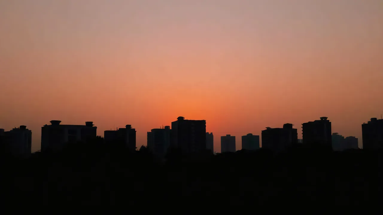 Silhouette of city buildings against a gradient dusk sky.