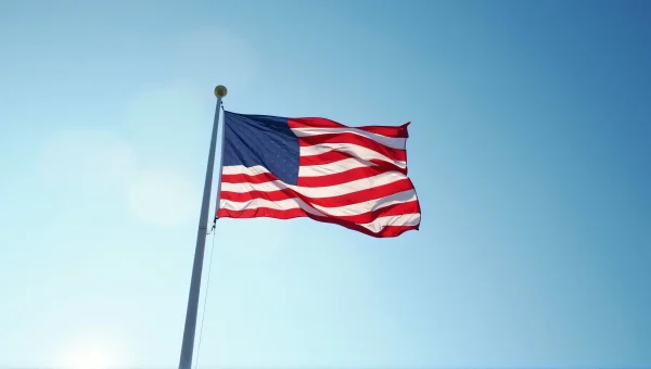 USA Flag Waving On Tall Pole Against Sky