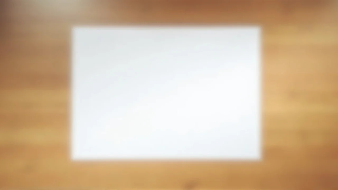 A single sheet of white printer paper on a wooden desk illuminated by soft overhead light.
