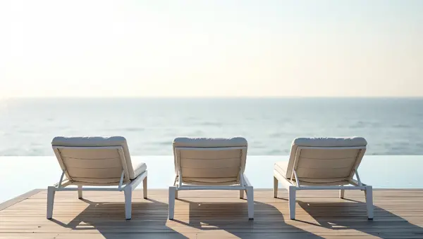 White Sun Loungers On Wooden Deck By Ocean