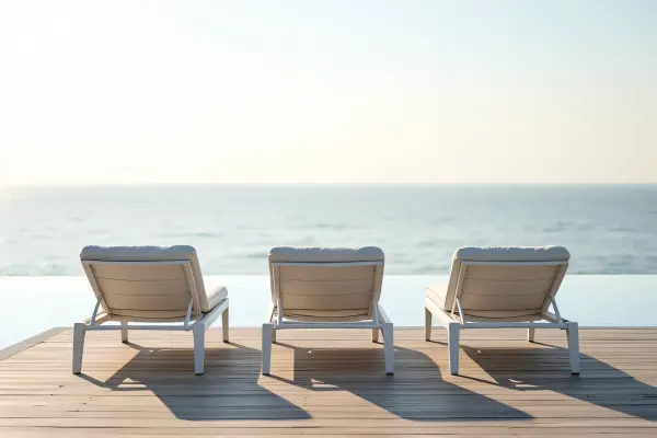 White Sun Loungers On Wooden Deck By Ocean