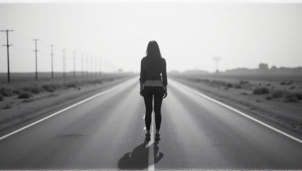 Woman Standing on Deserted Road in Grayscale